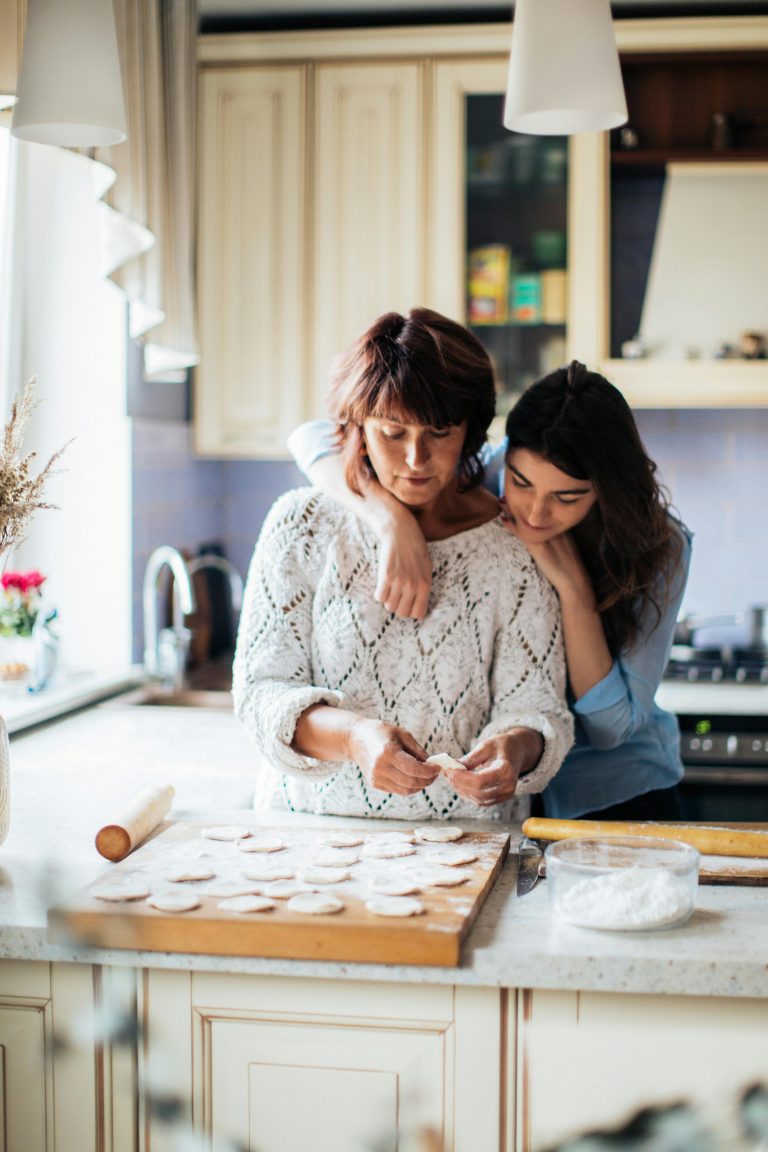 A mother and daughter bond while preparing traditional dumplings in a cozy kitchen setting.