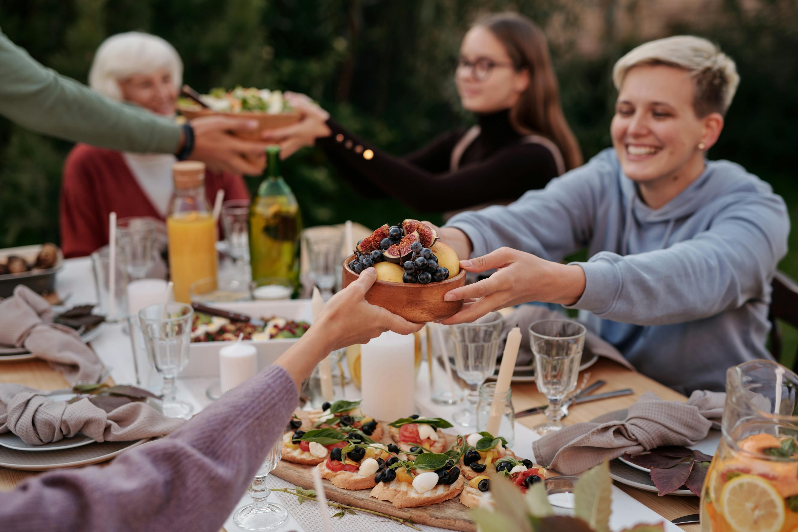 Joyful family gathering outdoors, featuring fruit bowls and shared meals on a beautifully set table.
